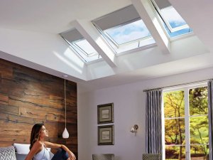 woman in bedroom looking up at skylights with blinds in auckland